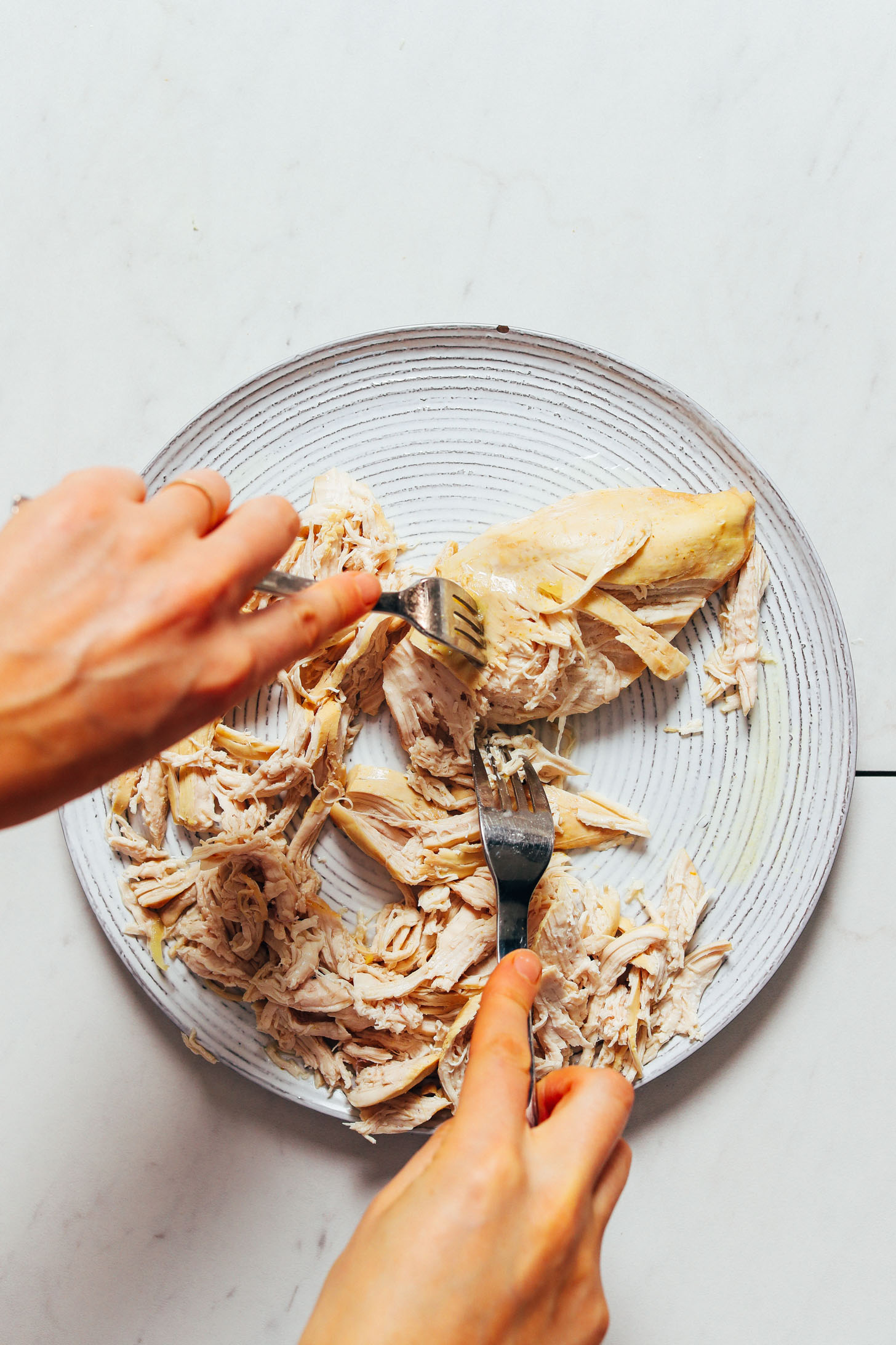 Using two forks to shred chicken breasts for Thai Chicken Noodle Soup