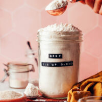 Picking up a spoonful of gluten-free flour blend from a jar