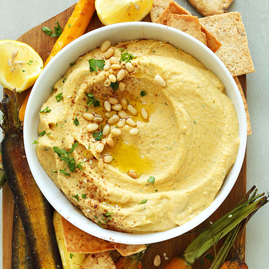 Top down shot of a big bowl of Butternut Squash Hummus with olive oil and pine nuts