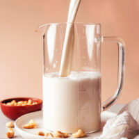 Pouring homemade cashew milk into a pitcher