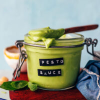 Spoonful of creamy pesto sauce resting on top of a jar of more sauce