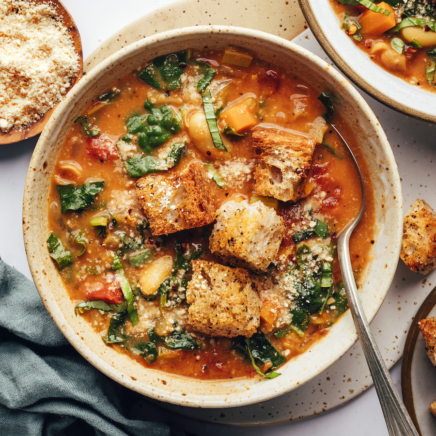 Gold spoon in a bowl of creamy tuscan soup with white beans and kale