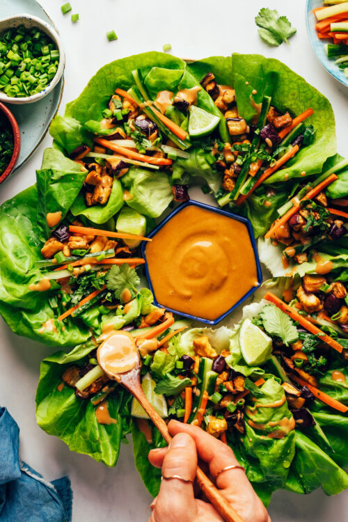 Drizzling a savory sesame sauce onto tofu and eggplant lettuce cups