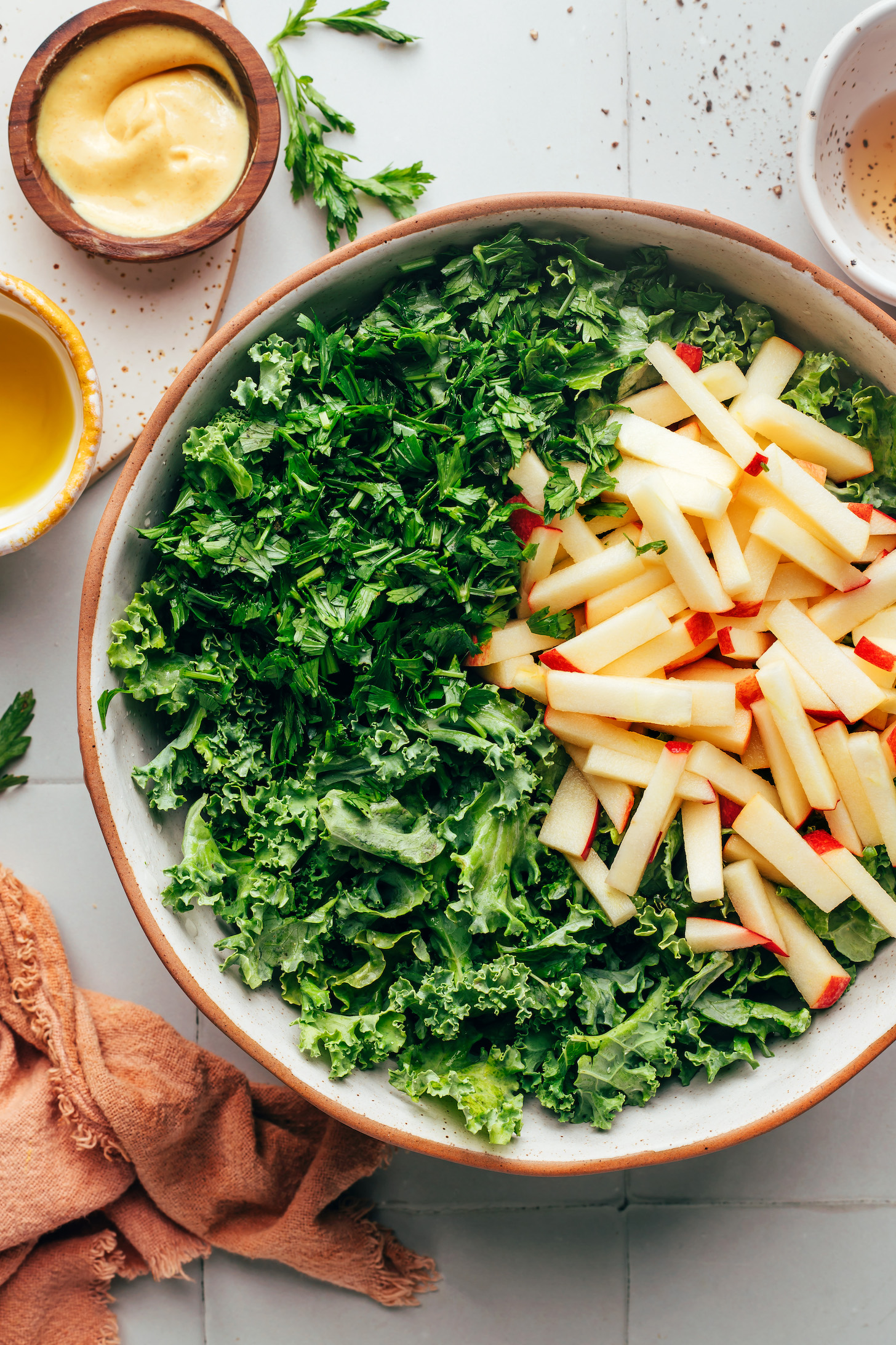 Bowl with chopped kale, apples cut into matchsticks, and fresh parsley