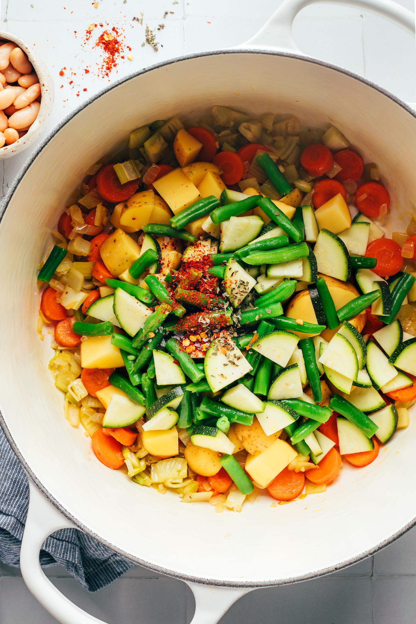 Dried basil and red pepper flakes over chopped green beans, zucchini, potatoes, and sautéed veggies