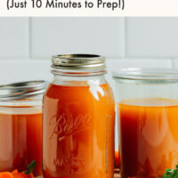 Jars of homemade vegetable broth next to ingredients used to make it