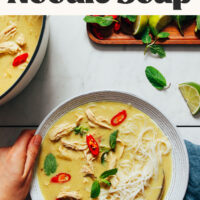 Holding a spoon and the side of a bowl of our cozy, 1-pot, Thai-inspired chicken noodle soup