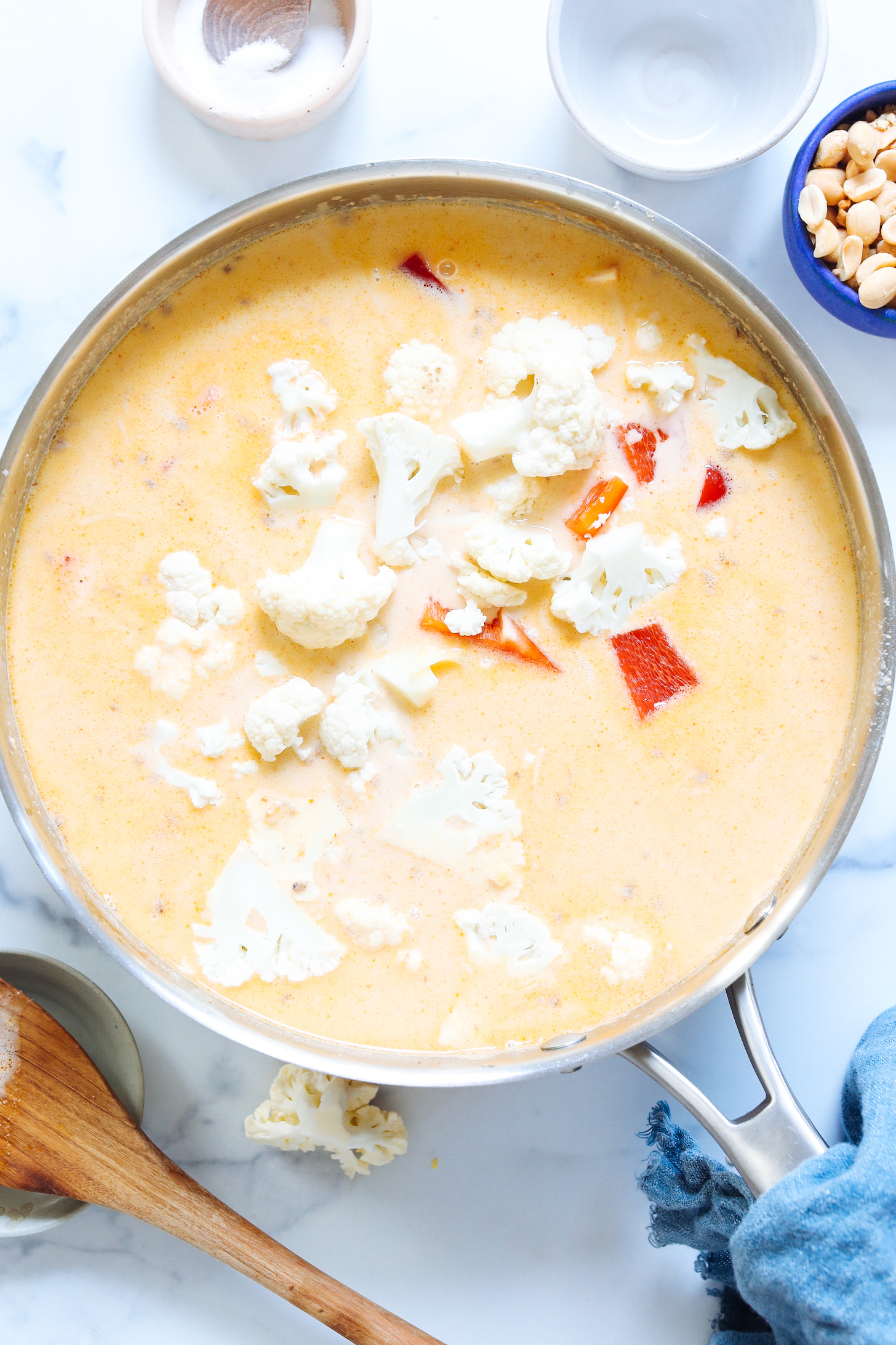 Cauliflower and bell pepper floating at the top of a pan of panang curry