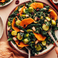 Using serving utensils to pick up a serving of our kale and roasted vegetable salad