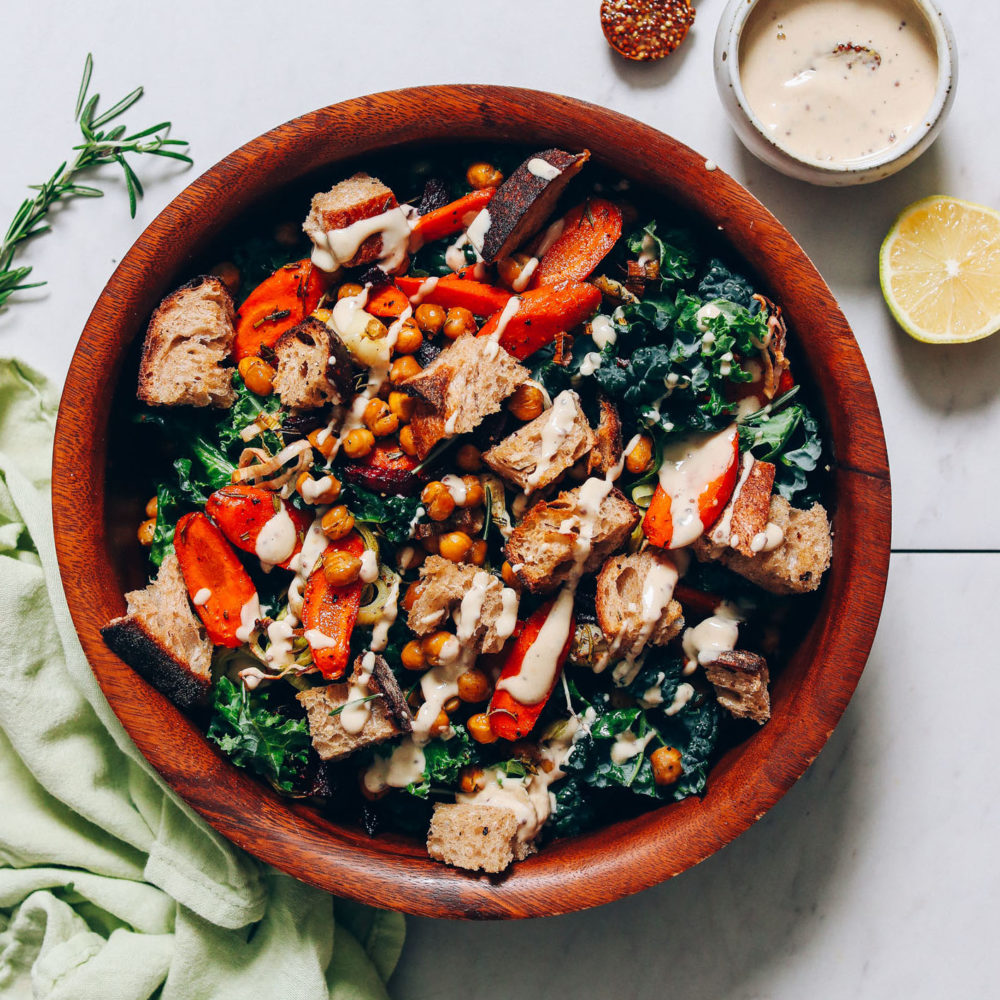 Tahini sauce next to a large bowl of Rosemary Roasted Root Vegetable Panzanella