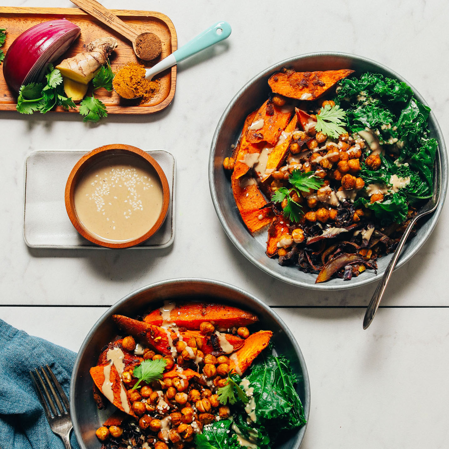 Bowls of our Sweet Potato Sheet Pan Dinner recipe beside a bowl of tahini sauce