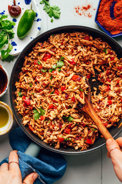 Using a wooden spoon to mix a skillet of our shredded tofu taco meat recipe