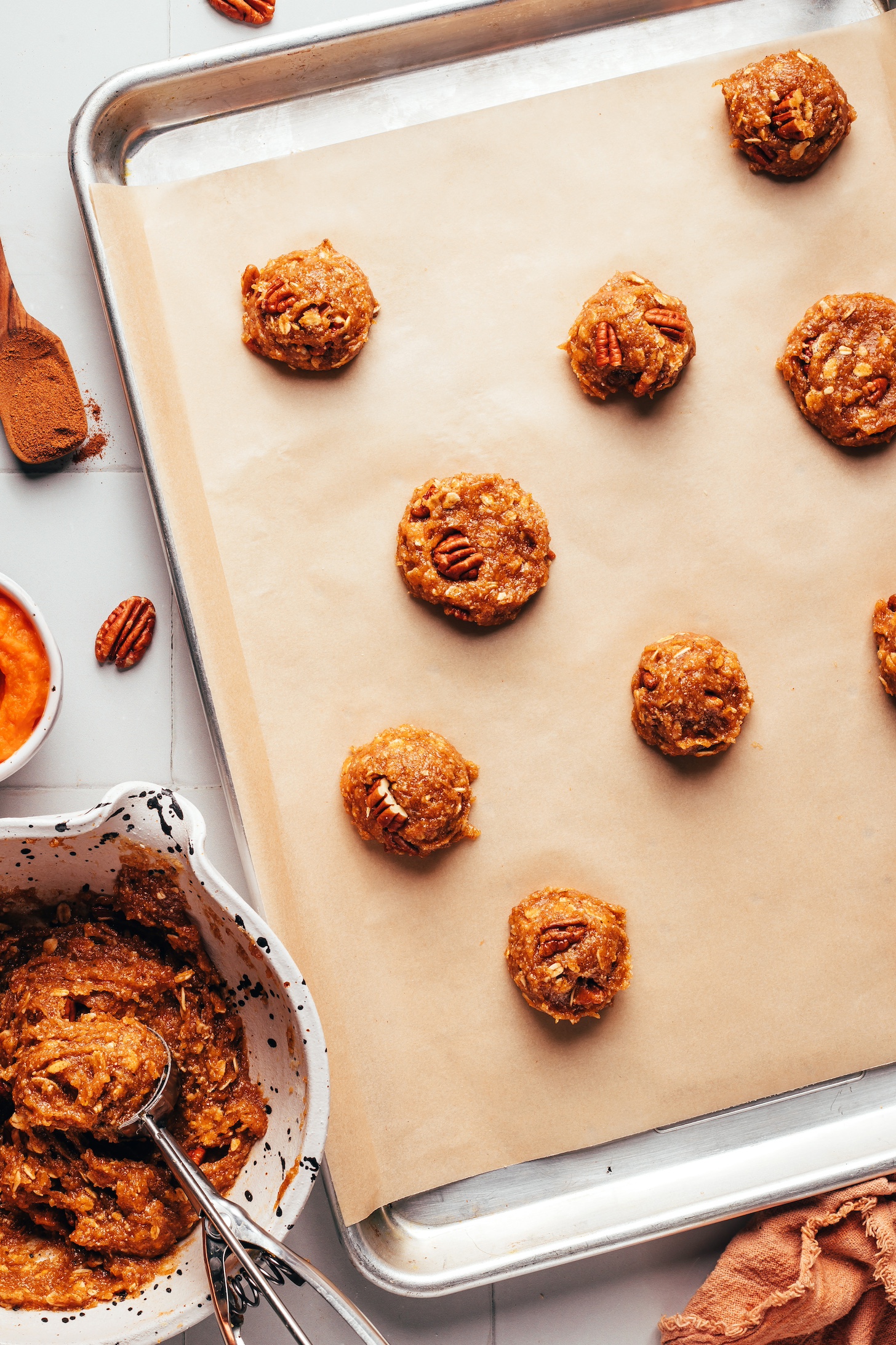 Bowl of cookie dough and a baking sheet with balls and discs of cookie dough 