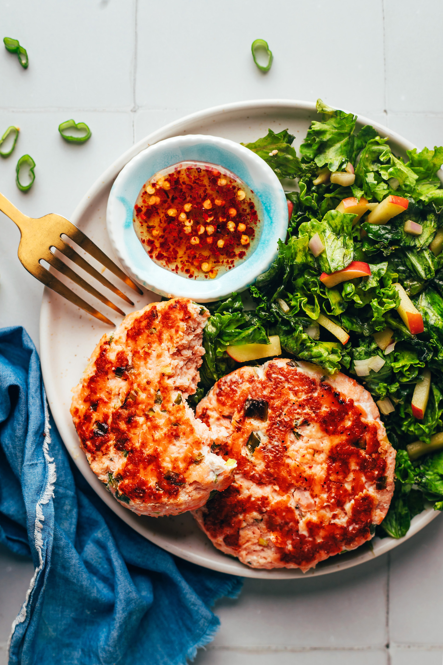 Plate with salmon burgers, kale apple slaw, and sweet chili sauce