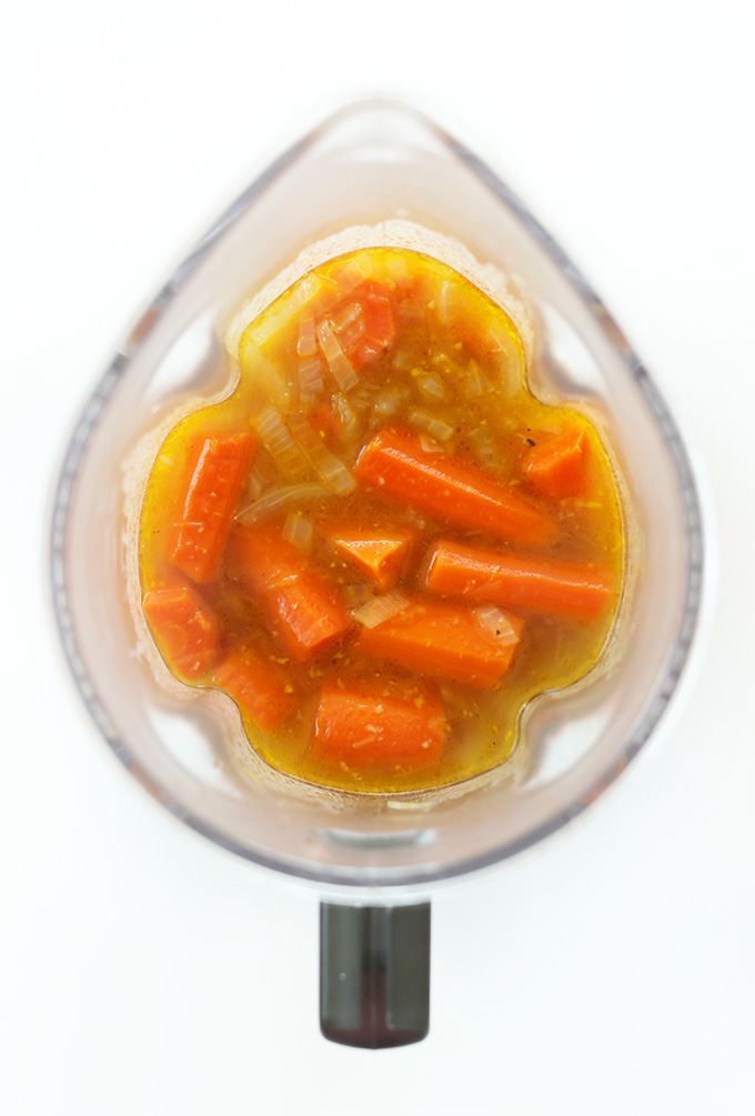 Blender with carrots, onions, and broth for making homemade vegan carrot soup