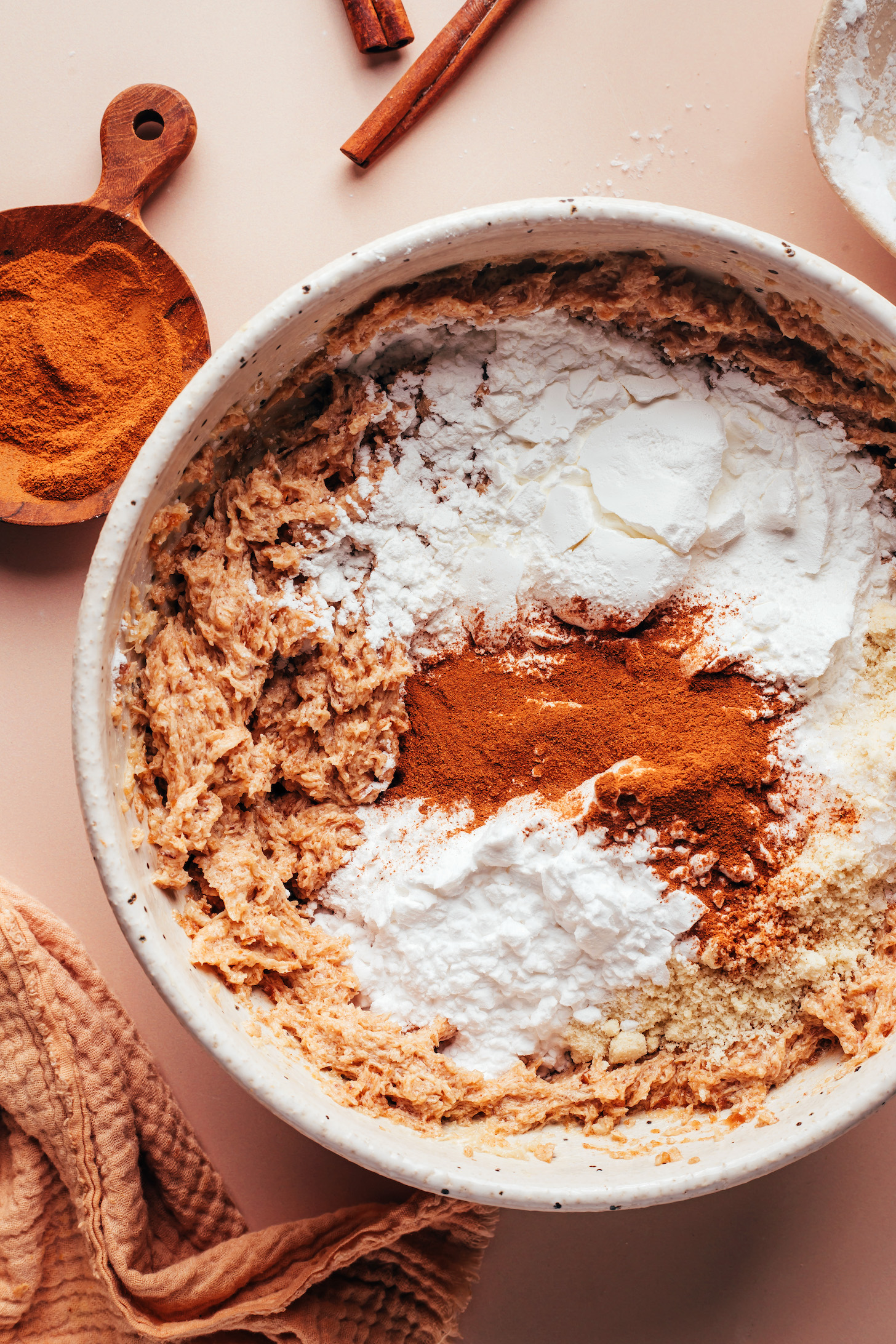 Almond flour, potato starch, arrowroot starch, and cinnamon over a bowl of whipped wet ingredients