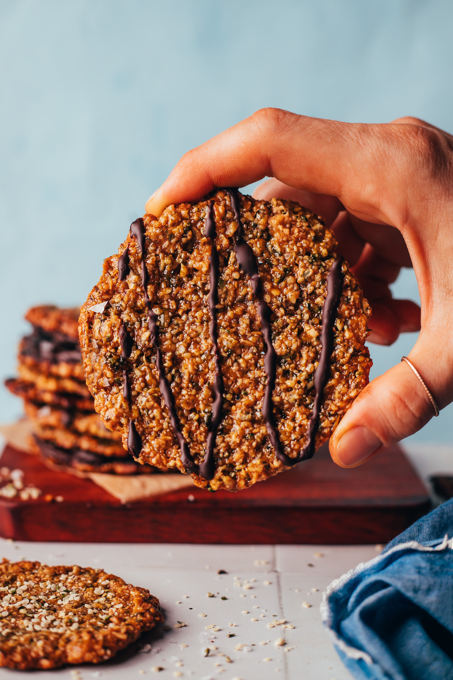 Holding up a hemp seed florentine cookie drizzled with melted dark chocolate