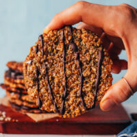 Holding up a vegan gluten-free florentine cookie drizzled with melted dark chocolate